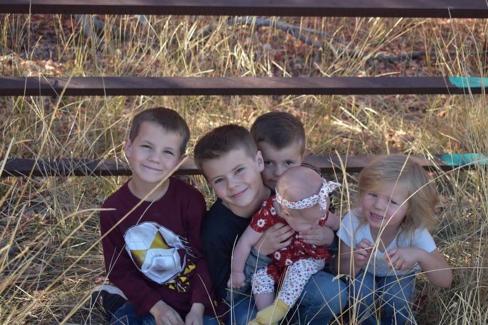 Children standing by a wooden fence in a rural community setting